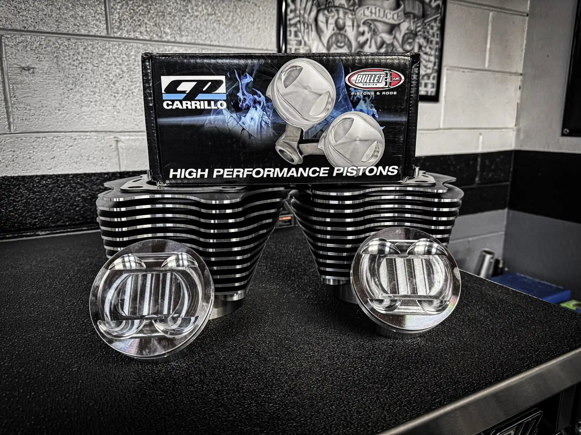 A set of high-performance engine pistons and cylinders, still in their packaging.